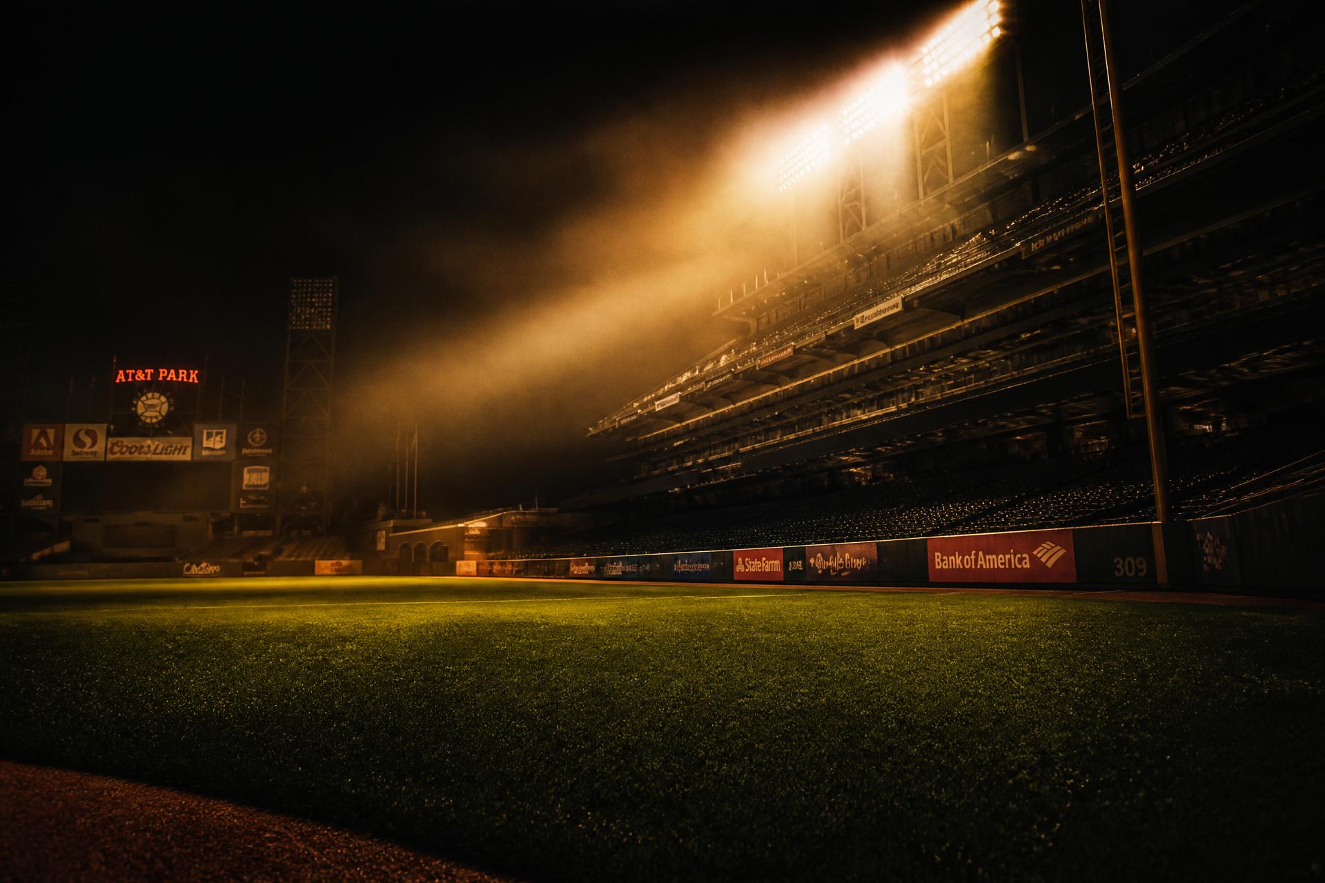 Empty baseball stadium at night lit by warm floodlights